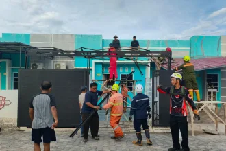 Sejumlah warga Perumahan Gladiola 1, Kelurahan Tebing, bersama personel BPBD Karimun gotong royong membongkar material kanopi rumah yang rusak berat akibat diterjang angin puting beliung, Selasa (14/4/2026) | Foto: Ami